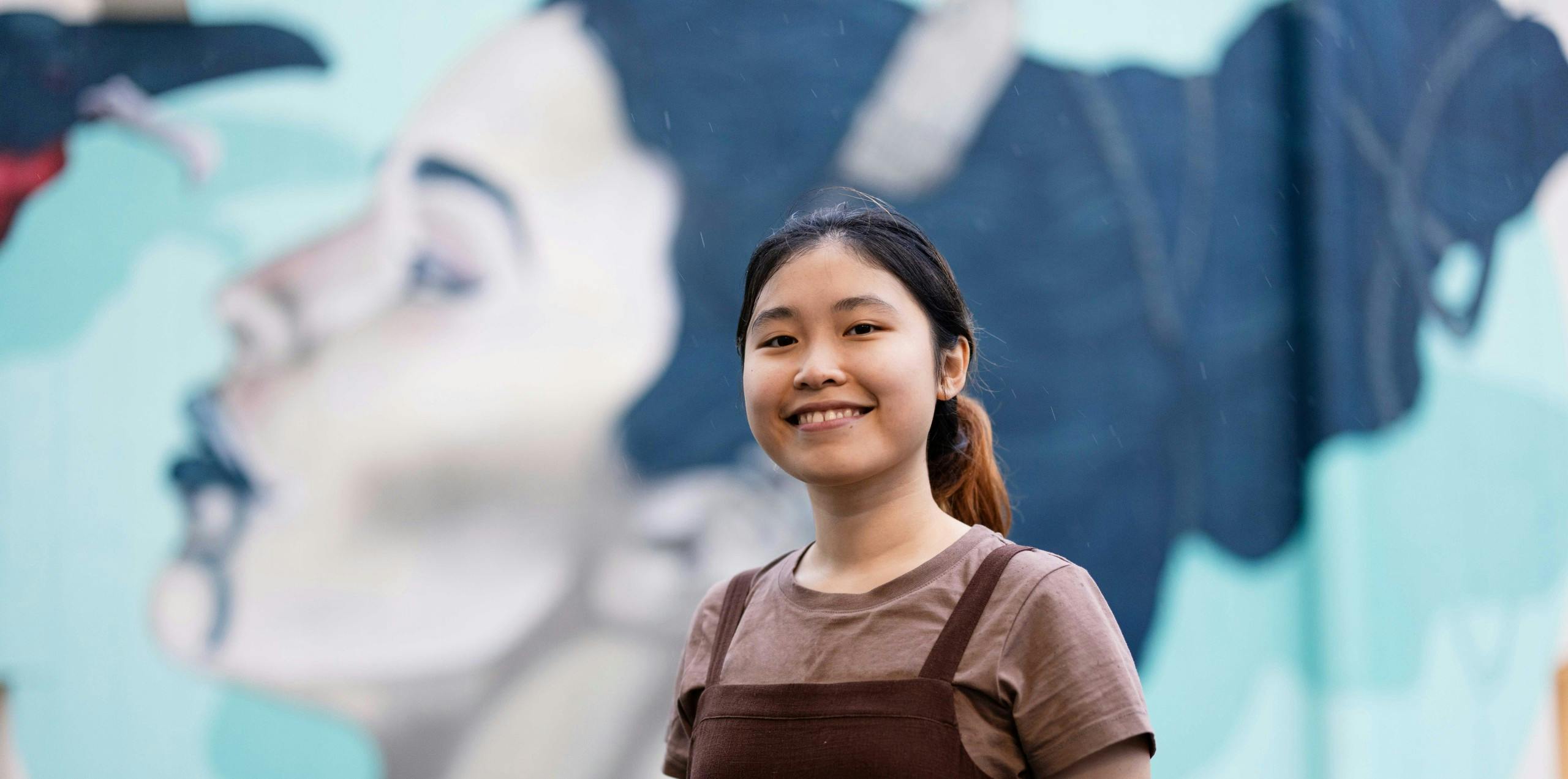 Vietnamese student in front of a mural in New Zealand