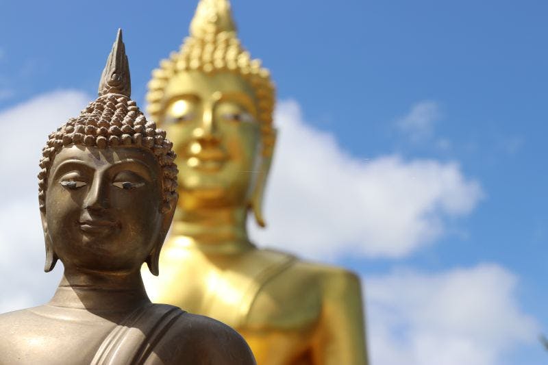 Two buddha statues photographed against the blue sky
