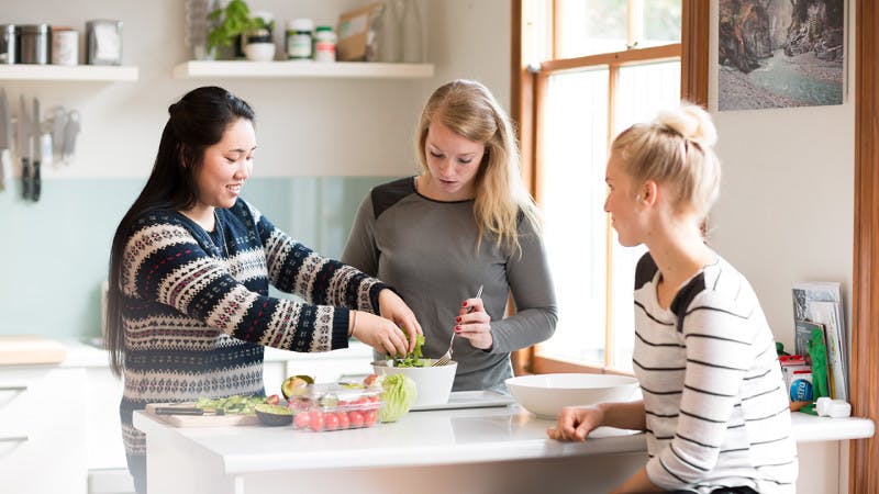 Three students are preparing a meal together in their shared house in New Zealand.