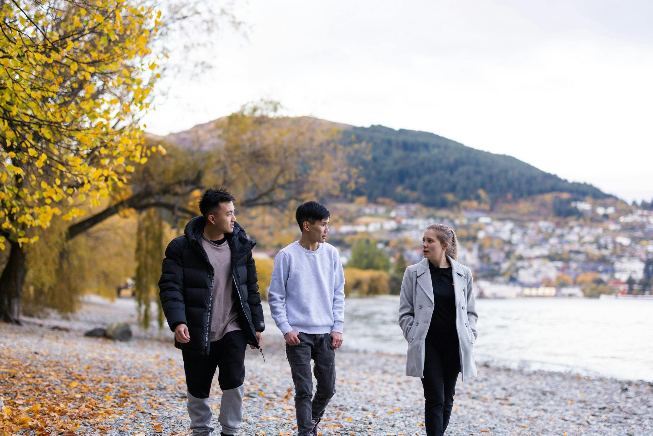 International students walking along a lake in Central Otago with mountains in the background.
