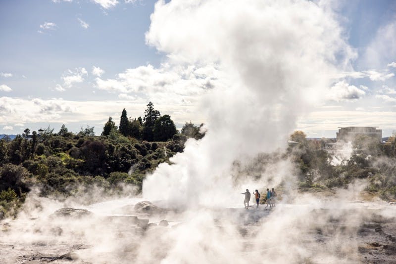 Tourists enjoying volcanic scenery with white smoke around them