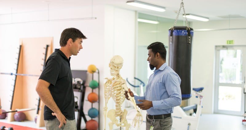 Two men in conversation in a physio's gym.