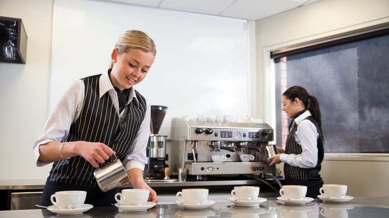 A hospitality student pouring coffee