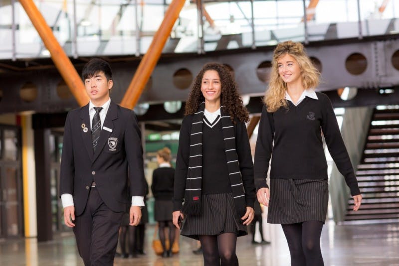 Three international and local high school students walking on campus