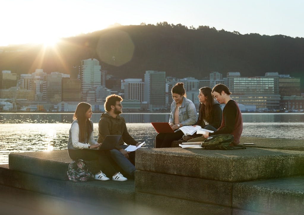 People sitting together near the harbour and having a discussion with laptops and books