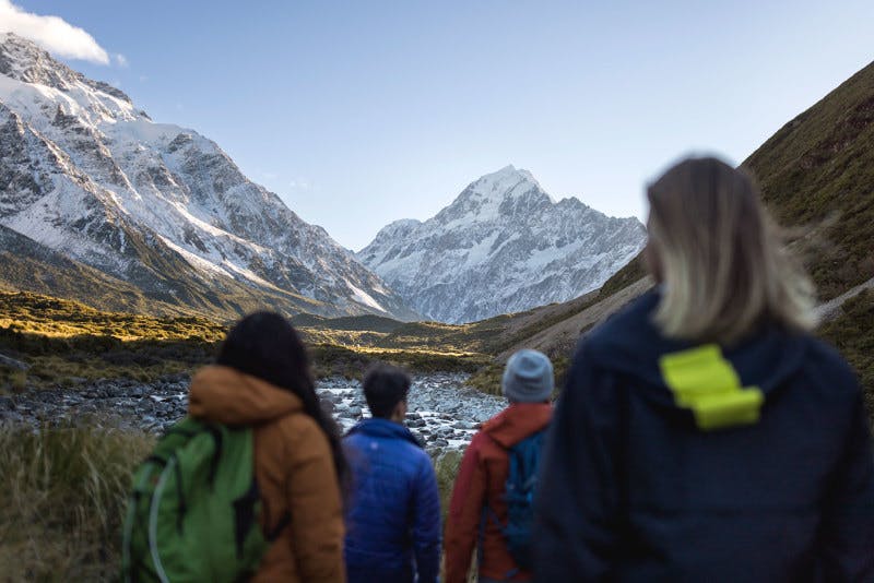 A group of people exploring the Hooker Valley walking towards Mt. Cook.