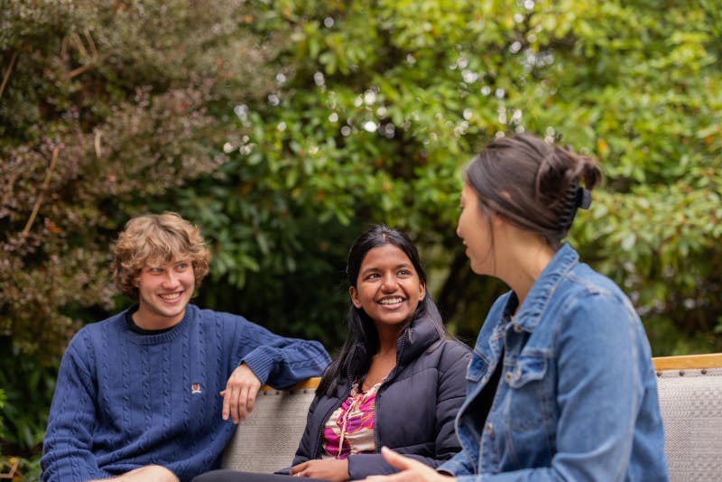 Students chatting happily on a bench